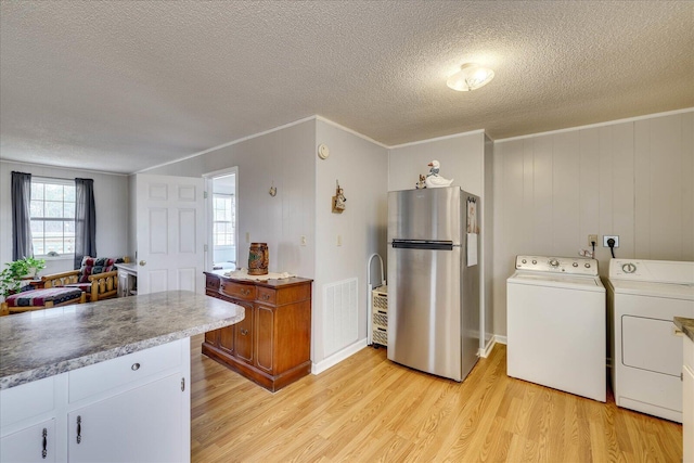 clothes washing area with ornamental molding, laundry area, light wood-style flooring, and washer and clothes dryer