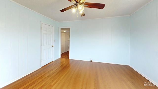 empty room featuring ceiling fan, wood finished floors, and crown molding