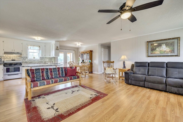 living room featuring light wood-style floors, a textured ceiling, and a ceiling fan