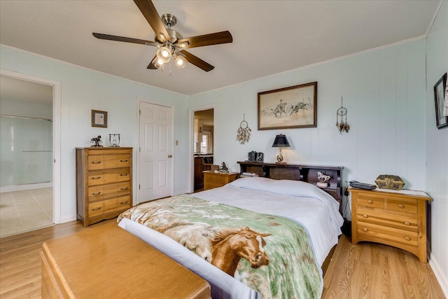 bedroom featuring light wood-style floors, ensuite bath, and a ceiling fan