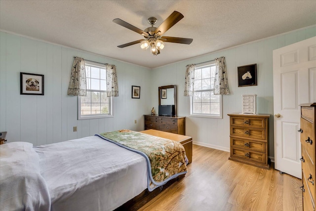 bedroom featuring a textured ceiling, light wood-type flooring, a ceiling fan, and crown molding