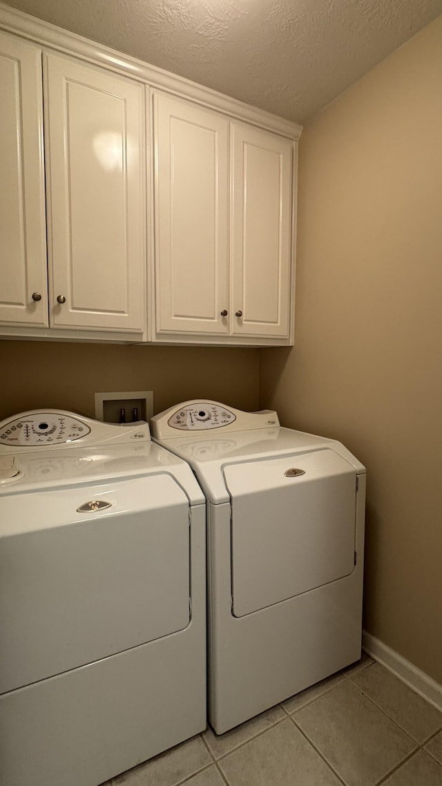 400 SE Pine Ave, Aiken, SC 29803 - laundry area with cabinet space, washing machine and clothes dryer, light tile patterned flooring, a textured ceiling, and baseboards
