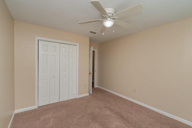 unfurnished bedroom featuring carpet, a textured ceiling, a closet, and ceiling fan