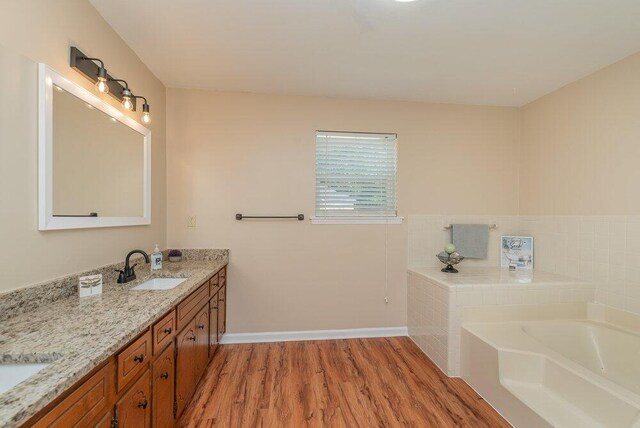 bathroom with vanity, hardwood / wood-style flooring, and a tub