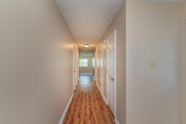 corridor with light hardwood / wood-style flooring and a textured ceiling