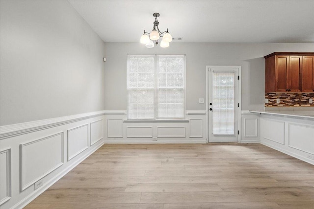 unfurnished dining area featuring an inviting chandelier and light hardwood / wood-style floors