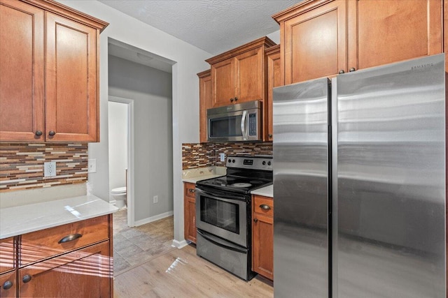 kitchen featuring tasteful backsplash, light hardwood / wood-style flooring, stainless steel appliances, and a textured ceiling