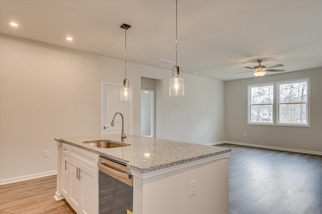 kitchen with white cabinetry, sink, light stone counters, stainless steel dishwasher, and decorative light fixtures