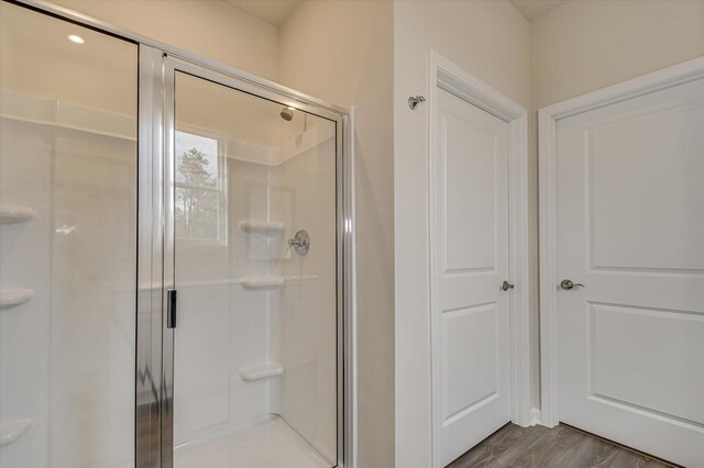 bathroom with wood-type flooring and an enclosed shower