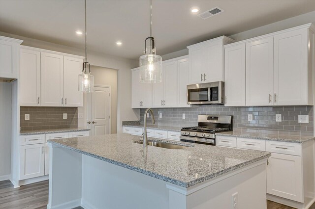 kitchen featuring stainless steel appliances, sink, pendant lighting, a center island with sink, and white cabinetry