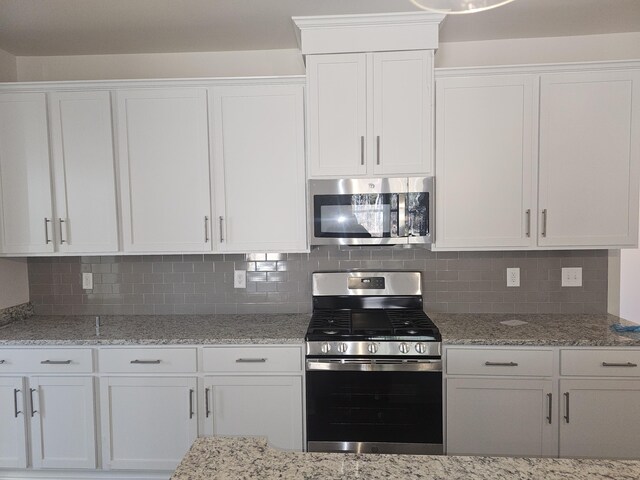 kitchen featuring backsplash, light stone counters, white cabinets, and appliances with stainless steel finishes