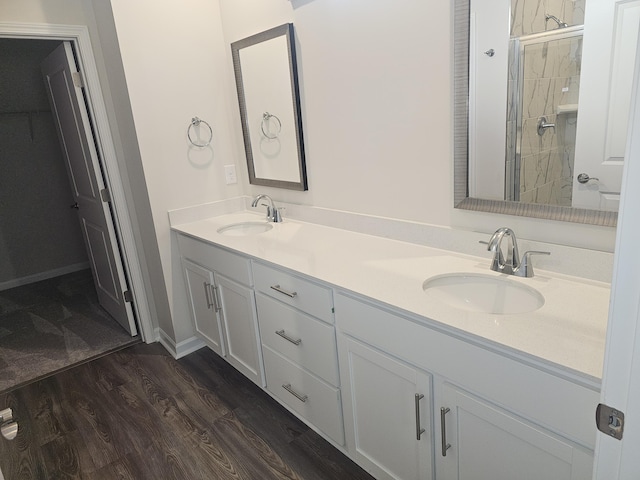 bathroom with tiled shower, wood-type flooring, and vanity