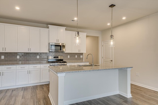 kitchen featuring a kitchen island with sink, sink, hanging light fixtures, and appliances with stainless steel finishes