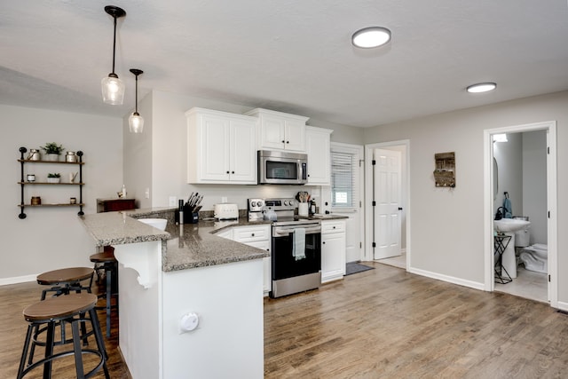 621 Cambridge Rd, Augusta, GA 30909 - kitchen featuring appliances with stainless steel finishes, a kitchen bar, light wood-style flooring, and a peninsula