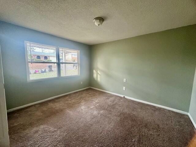 carpeted empty room featuring a textured ceiling and baseboards