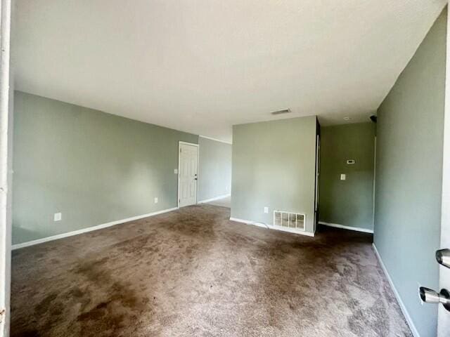 empty room with dark colored carpet, visible vents, and baseboards