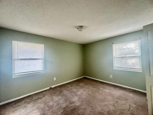 unfurnished room with a textured ceiling, carpet flooring, and baseboards