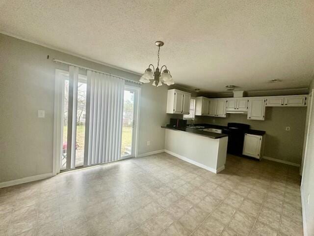 kitchen with light floors, dark countertops, hanging light fixtures, white cabinets, and a peninsula