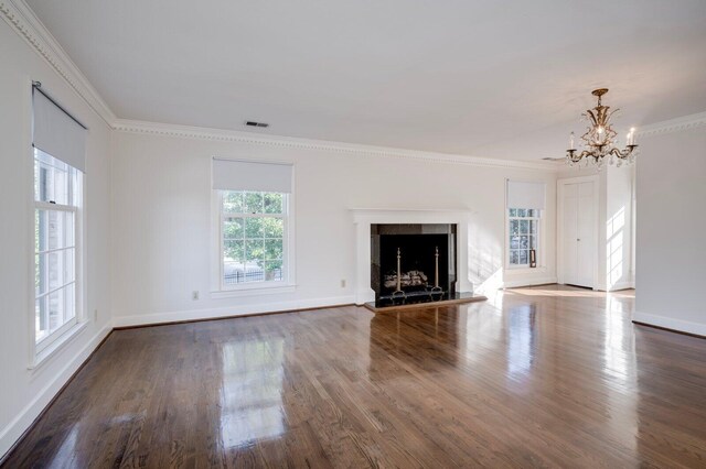 unfurnished living room featuring crown molding, a fireplace, dark wood-type flooring, and a notable chandelier