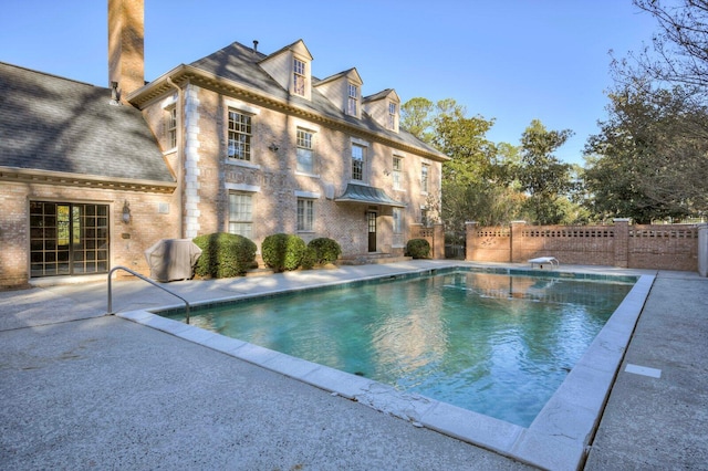 view of swimming pool featuring a diving board and a patio