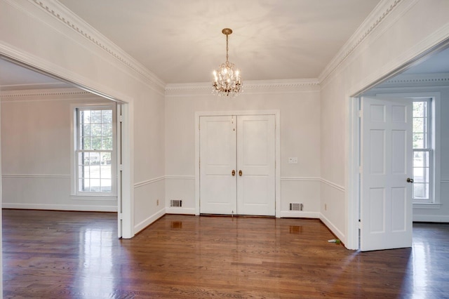 foyer entrance with dark hardwood / wood-style flooring, an inviting chandelier, plenty of natural light, and ornamental molding