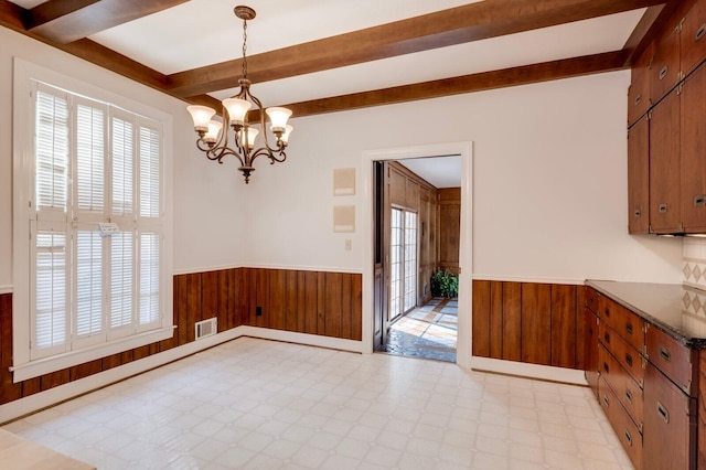 unfurnished dining area featuring a chandelier and wood walls