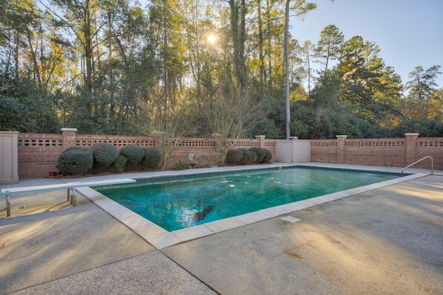 view of swimming pool featuring a diving board and a patio area