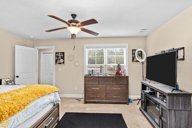 bedroom with light colored carpet, baseboards, a textured ceiling, and ceiling fan