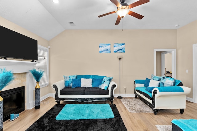 living room with wood finished floors, visible vents, baseboards, vaulted ceiling, and a glass covered fireplace