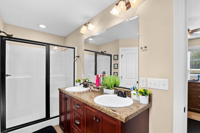 full bath featuring double vanity, a shower stall, ceiling fan, and a sink