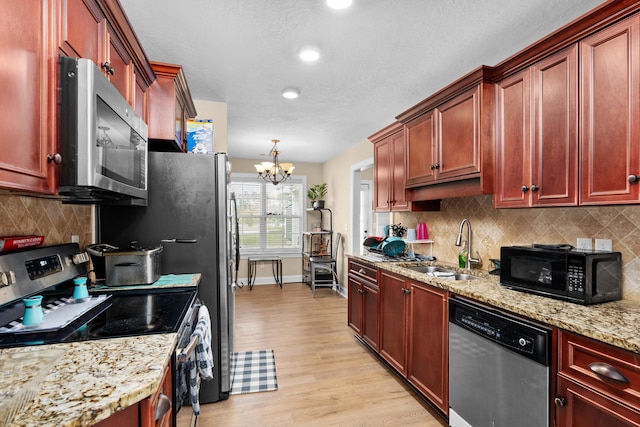 kitchen with a sink, stainless steel appliances, light wood finished floors, baseboards, and dark brown cabinets