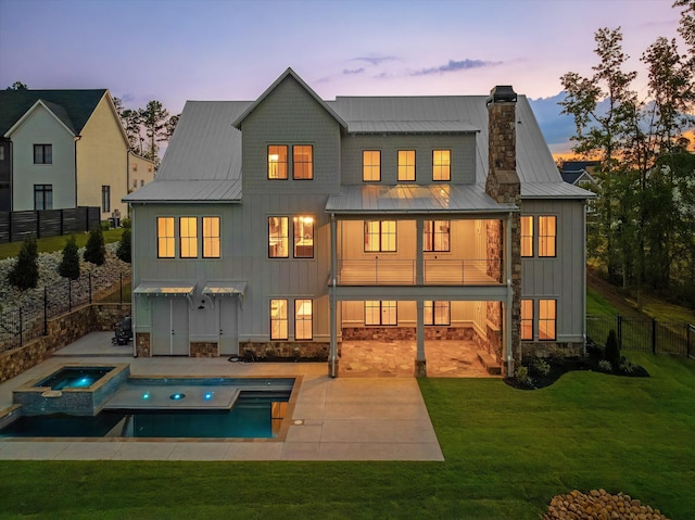 811 Audubon Way, Evans, GA 30809 - back of property at dusk with a standing seam roof, board and batten siding, a balcony, a chimney, and a patio area