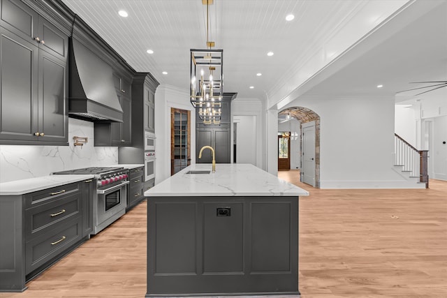 811 Audubon Way, Evans, GA 30809 - kitchen with high end stainless steel range, premium range hood, crown molding, a center island with sink, and light wood-style flooring