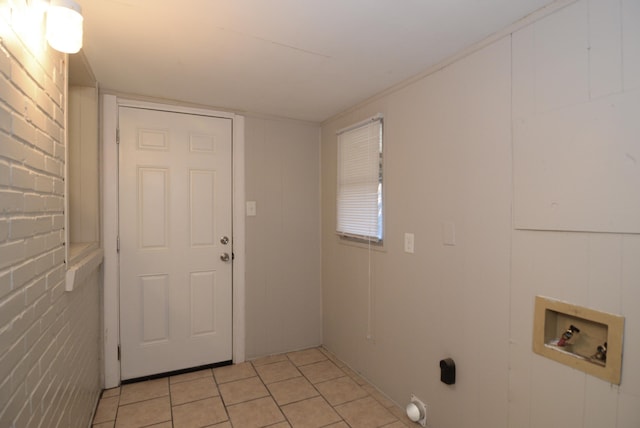 clothes washing area with brick wall and hookup for a washing machine