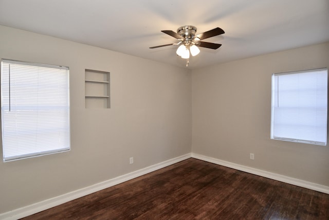 empty room featuring dark hardwood / wood-style floors, built in features, and ceiling fan