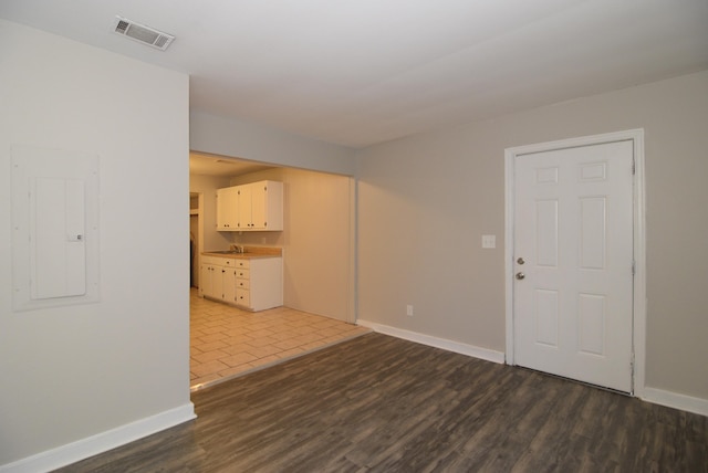 empty room with dark hardwood / wood-style floors and electric panel