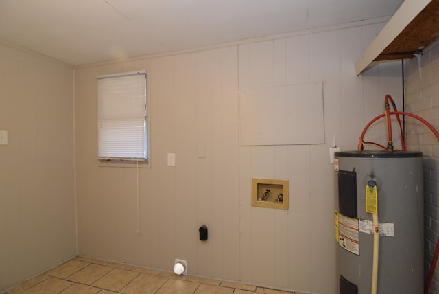 clothes washing area with water heater, hookup for a washing machine, light tile patterned floors, and wood walls