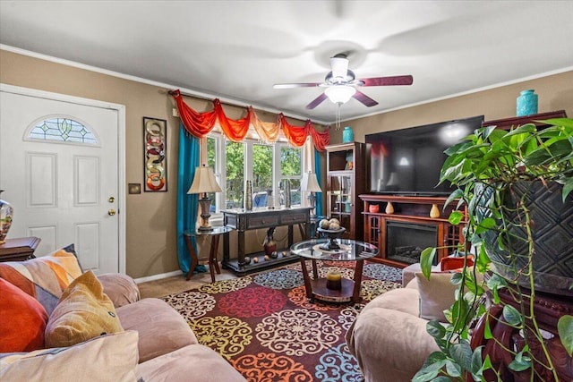 living room with ceiling fan, plenty of natural light, baseboards, crown molding, and carpet
