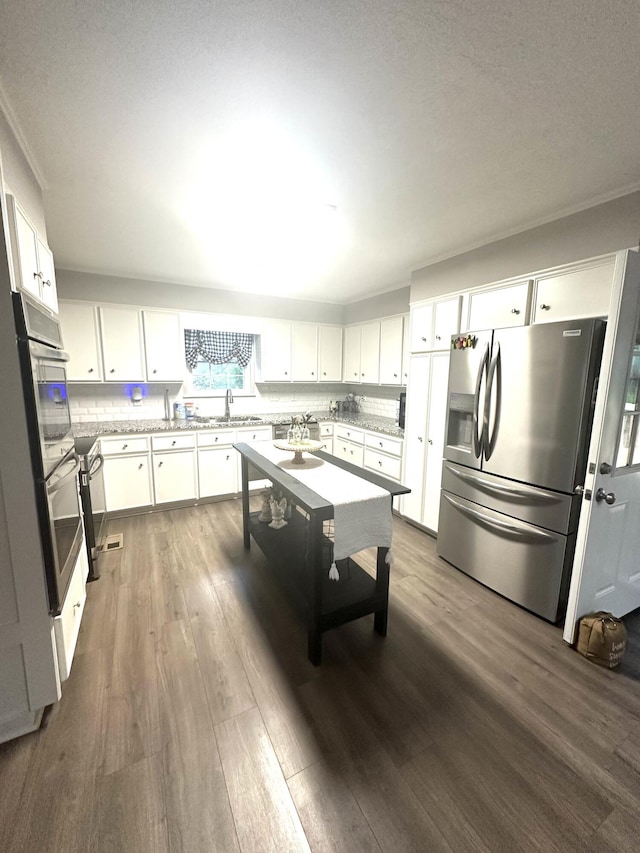 4690 Red Leaf Way, Augusta, GA 30907 - kitchen featuring appliances with stainless steel finishes, dark wood-type flooring, white cabinets, a sink, and tasteful backsplash