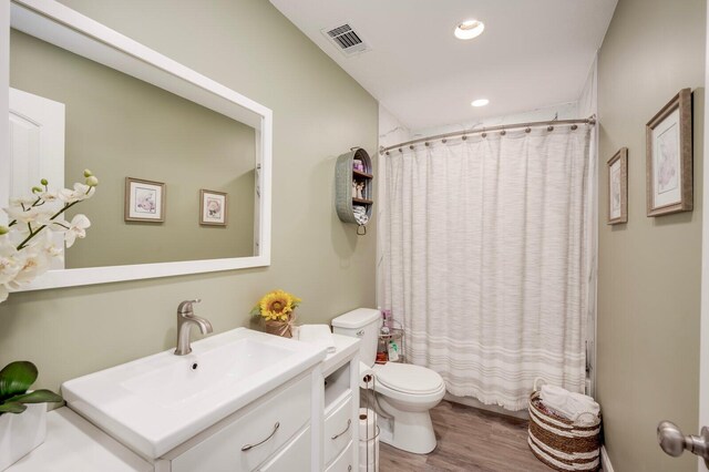 full bathroom with hardwood / wood-style floors, vanity, toilet, and shower / bath combo with shower curtain