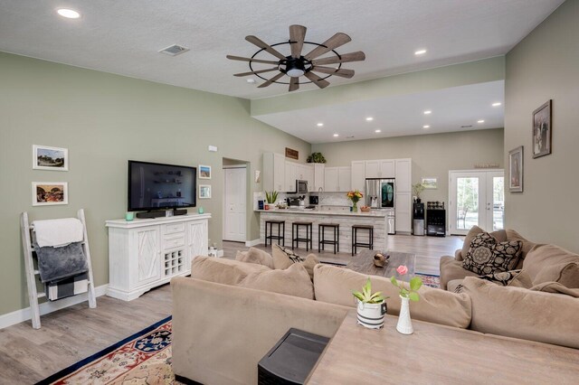 living room featuring french doors, a textured ceiling, light hardwood / wood-style flooring, and ceiling fan