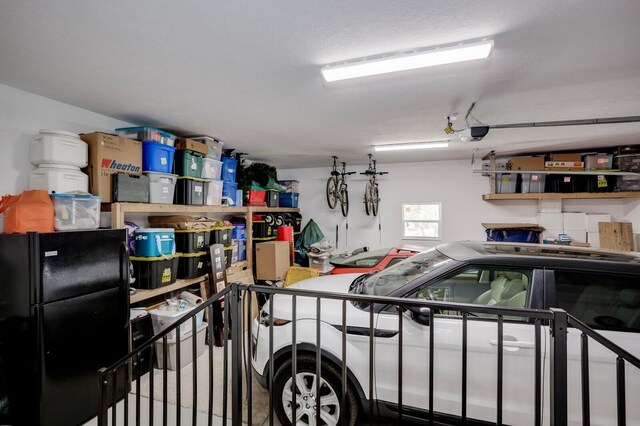 garage with a garage door opener and black fridge