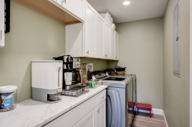 laundry area featuring washer and clothes dryer, cabinets, and light wood-type flooring