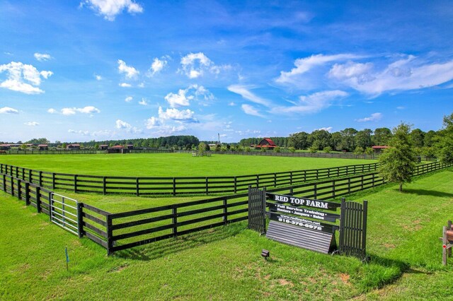 view of gate featuring a lawn and a rural view