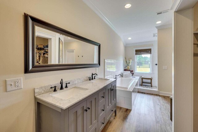 bathroom featuring tiled bath, crown molding, vanity, and hardwood / wood-style flooring