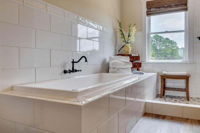 bathroom with wood-type flooring and tiled bath