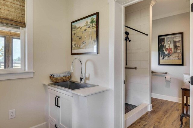 bathroom featuring a tile shower, vanity, ornamental molding, and hardwood / wood-style flooring