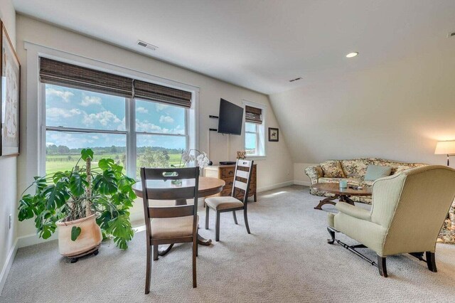 carpeted dining area featuring lofted ceiling