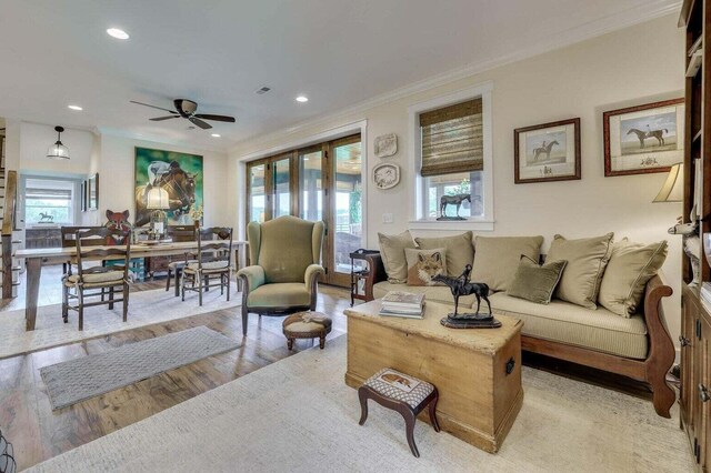 living room featuring ornamental molding, light hardwood / wood-style floors, ceiling fan, and a healthy amount of sunlight