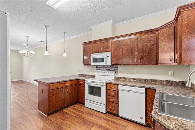 kitchen featuring ornamental molding, white appliances, sink, decorative light fixtures, and a notable chandelier